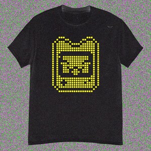 May include: Black t-shirt with a yellow pixelated graphic of a handheld gaming device. The design is in the centre of the shirt. The t-shirt has short sleeves and a crew neck.
