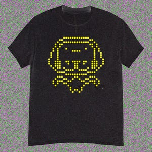 May include: Black t-shirt with a yellow pixelated dog graphic. The dog has large ears and a bow tie. The design is in the centre of the shirt. The t-shirt has short sleeves and a crew neck.