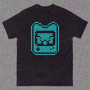 May include: Black t-shirt with a teal pixelated graphic of a handheld gaming device. The design is made up of small squares, giving it a retro look. The shirt has a classic crew neck.