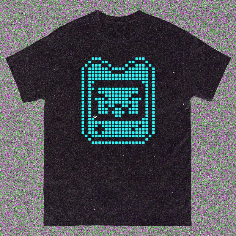 May include: Black t-shirt with a teal pixelated graphic of a handheld gaming device. The design is made up of small squares, giving it a retro look. The shirt has a classic crew neck.