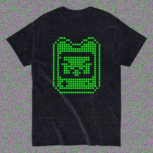May include: Black t-shirt with a green pixelated graphic of a handheld gaming device. The design is in the centre of the shirt. The t-shirt has short sleeves and a crew neck.