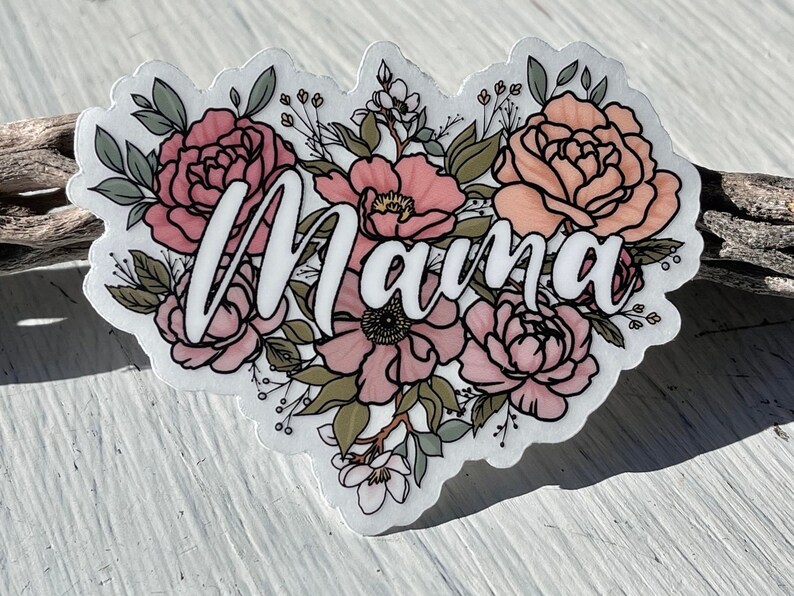 May include: A white sticker with the word "Mama" in cursive script surrounded by pink and peach flowers with green leaves.