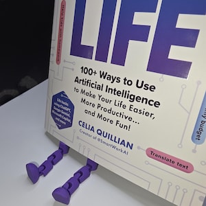 Puede incluir: Un libro titulado "100+ Ways to Use Artificial Intelligence to Make Your Life Easier, More Productive... and More Fun!" de Celia Quillian, Creadora de @SmartWorkAI. La portada del libro presenta un diseño degradado en púrpura y azul con la palabra "LIFE" en letras grandes y en negrita.