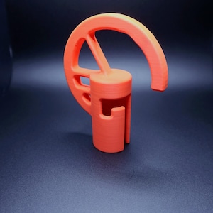 Könnte beinhalten: Ein 3D-gedruckter spartanischer Helm aus orangefarbenem Kunststoff mit einem kreisförmigen Design auf der Oberseite.