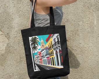 May include: Black tote bag with a colorful illustration of a street scene with palm trees and buildings. The buildings are painted in shades of yellow, pink, blue, and green.