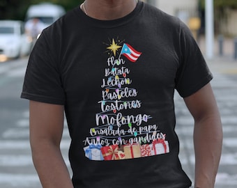 May include: Black t-shirt with a Christmas tree design made of Puerto Rican food names and a Puerto Rican flag. The tree is decorated with string lights and presents at the base.
