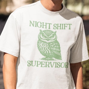May include: White t-shirt with a green owl graphic and the text "NIGHT SHIFT SUPERVISOR".