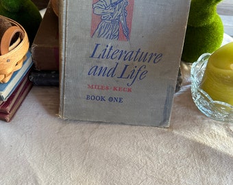 May include: A vintage book titled "Literature and Life" by Miles Keck, Book One. The cover features a blue illustration of a man in a colonial-era uniform carrying a rifle and a bird perched on his shoulder.