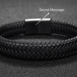 May include: Black braided leather bracelet with a stainless steel clasp. The bracelet features a woven design and a magnetic closure. The text "Secret Message" is above the clasp. This accessory is suitable for everyday wear.