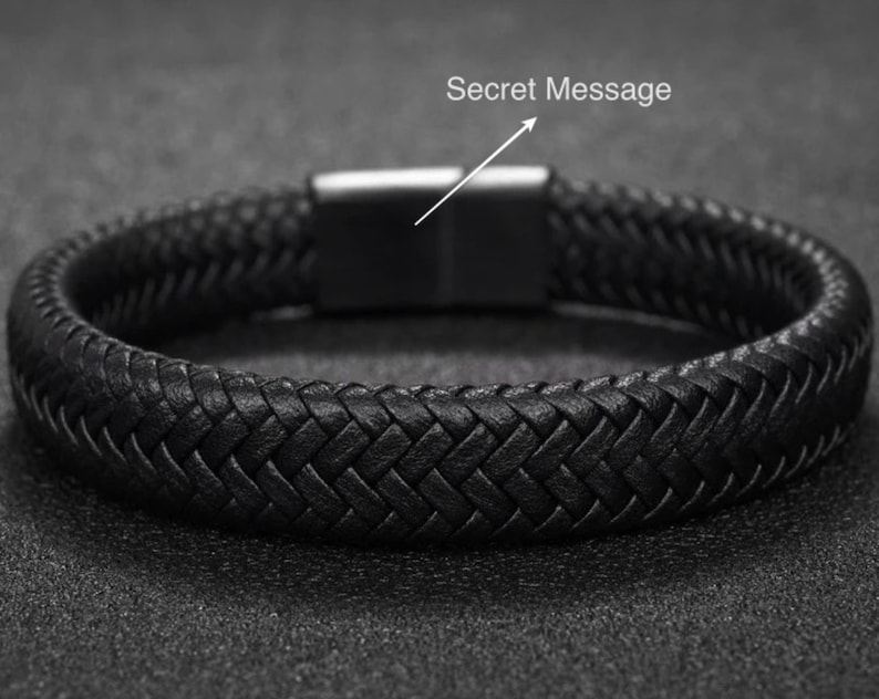 May include: Black braided leather bracelet with a stainless steel clasp. The bracelet features a woven design and a magnetic closure. The text "Secret Message" is above the clasp. This accessory is suitable for everyday wear.