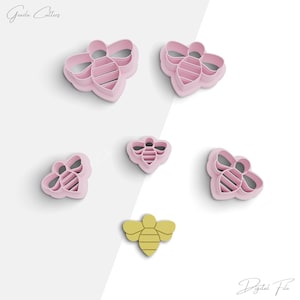 May include: Set of six pink bee-shaped cookie cutters, including one smaller yellow bee cutter. The cutters are designed for baking and decorating cookies.