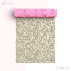 Puede incluir: Un rodillo de silicona rosa y beige con un patrón floral. El rodillo está enrollado y el patrón es visible en ambos lados, rosa y beige.