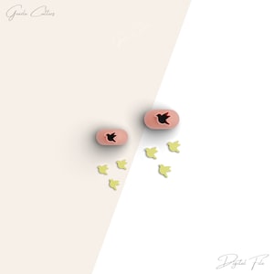 May include: Two pink silicone cookie cutters shaped like birds, with one bird inside the other. Five yellow silicone cookie cutters shaped like flying birds are scattered around the pink cutters.