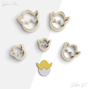May include: Set of six cookie cutters shaped like cracked eggs. The cutters are made of a light beige plastic. The cutters are arranged in a random pattern on a white background.