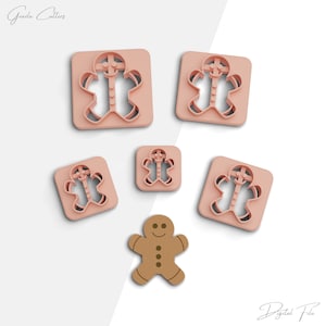 May include: Set of five gingerbread man cookie cutters in pink plastic. The cutters are in different sizes and feature a gingerbread man design with buttons and a smile. There is also a gingerbread man cookie in the centre of the image.