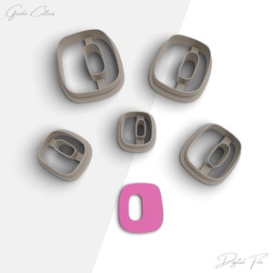 Puede incluir: Conjunto de seis cortadores de galletas de plástico en forma de número cero. Los cortadores son de diferentes tamaños y están dispuestos sobre una superficie blanca. Un recorte de plástico rosa del número cero se encuentra en el centro de la imagen.