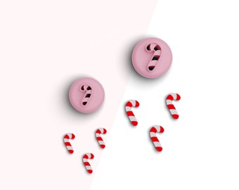 May include: A set of pink candy cane cookie cutters. The set includes two large cutters and six small cutters. The cutters are on a white and pink background.