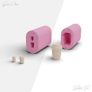 Op de afbeelding: Roze siliconen mal voor het maken van kleine koffiekopjes. De mal is open en laat de twee holtes voor de kopjes zien. Er zijn drie kleine koffiekopjes gemaakt met de mal.