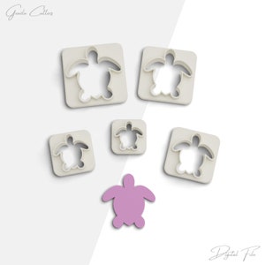 May include: Five white plastic turtle cookie cutters of varying sizes, with a single purple turtle cookie cutter in the centre.