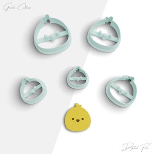 May include: Five cookie cutters in the shape of a chick. The cutters are light blue and have a white outline. There is also a yellow chick cookie cutter with a white outline.