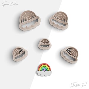 Puede incluir: Conjunto de seis cortadores de galletas de arcoíris y nubes. Los cortadores están hechos de plástico y son de varios tamaños. El cortador más grande es un arcoíris con una nube debajo. El cortador más pequeño es un arcoíris con una nube debajo. Los cortadores están dispuestos sobre un fondo blanco.
