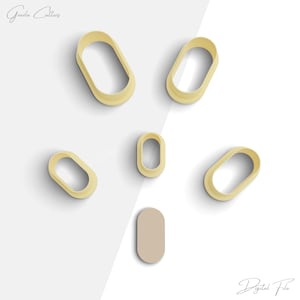 May include: Set of six oval-shaped cookie cutters in various sizes. The cutters are made of a light yellow plastic and are arranged on a white background. The largest cutter is approximately 3 inches long.