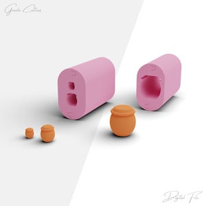May include: Two pink silicone moulds for making small clay pots. The moulds are open and show the inside of the pot shapes. There are three small clay pots, one large and two small, in the image.