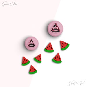 Pode incluir: Dois cortadores de biscoitos de melancia de plástico rosa, um inteiro e outro em fatias, com seis formas de fatias de melancia vermelhas e verdes.