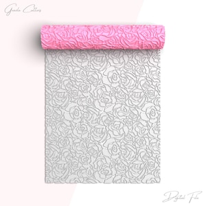 May include: A pink silicone rolling pin with a rose pattern. The rolling pin is rolled out to show the pattern on the surface. The pattern is a repeating design of roses.