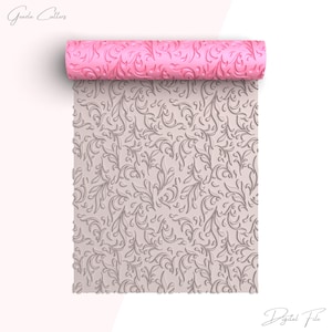 Puede incluir: Un rodillo rosa con un diseño floral en relieve se desenrolla sobre una superficie beige claro, revelando un patrón a juego. El texto "Graeda Cutters" y "Digital File" está presente.