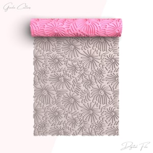 Puede incluir: Un rodillo rosa con un diseño floral descansa sobre una lámina en relieve con un patrón a juego de flores y hojas. La imagen incluye el texto "Greeda Cutters" y "Digital File". La lámina en relieve es para hornear.