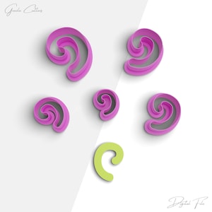 May include: Set of six pink and green plastic cookie cutters shaped like swirls. The cutters are arranged on a white background.