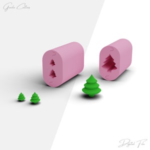 May include: Two pink silicone molds for making Christmas tree shapes. The molds are open and show the tree shapes inside. There are three green plastic Christmas trees of different sizes.
