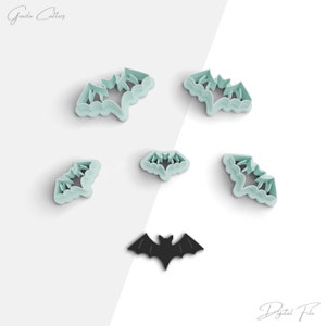 Puede incluir: Un conjunto de cortadores de galletas con forma de murciélago en color verde azulado claro y una silueta de murciélago negro. Los cortadores están dispuestos sobre un fondo blanco. El texto "Grazia Cutters" y "Digital File" está en la imagen.