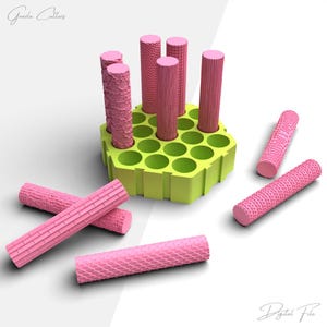 以下が含まれることがあります： レンガ、鱗、リブなどの模様が施された、ピンク色の円筒形のツールコレクション。円形の開口部があるライムグリーンの六角形のホルダーに収められています。