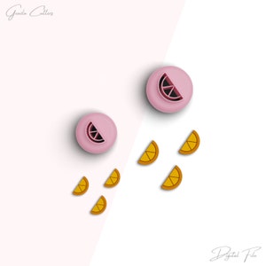 May include: Two pink cookie cutters shaped like a lemon wedge, with five orange cookie cutters shaped like lemon slices on a white and pink background.  The text "Gazda Cutters" is in the top left corner of the image.  The text "Digital File" is in the bottom right corner of the image.