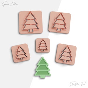May include: Five pink plastic cookie cutters shaped like Christmas trees, with one green plastic cookie cutter shaped like a Christmas tree.