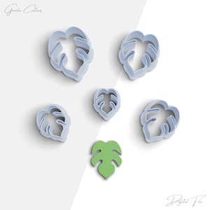 Puede incluir: Un conjunto de cortadores de galletas de plástico azul claro con forma de hoja y un cortador de galletas verde con forma de hoja. Los cortadores son de varios tamaños y formas, perfectos para crear golosinas con temática tropical. El texto "Grada Cutters" y "Digital File" es visible.