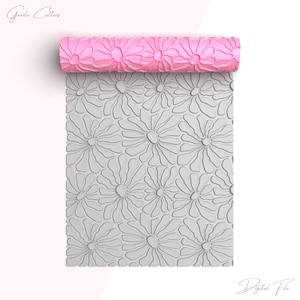 May include: A pink rolling pin with a daisy pattern. The rolling pin is unrolled and shows the pattern on the surface.