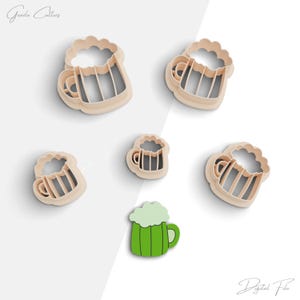 May include: Set of five cookie cutters shaped like beer mugs. The cutters are made of plastic and are beige in color. The cutters are arranged on a white background. The largest cutter is at the top of the image, and the smallest cutter is at the bottom. The cutters are all in focus.