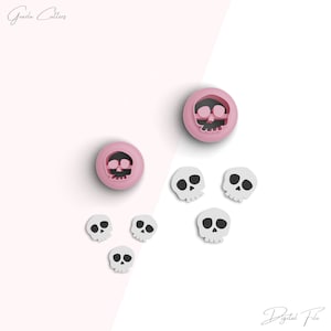 May include: A set of six skull-shaped cookie cutters. Two of the cutters are pink and four are white. The cutters are arranged on a white and pink background. The text "Goodie Cutters" is in the top left corner of the image. The text "Digital File" is in the bottom right corner of the image.