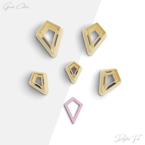 May include: Six cookie cutters in the shape of a diamond, with a seventh smaller diamond cutter in pink. The cutters are made of a light beige plastic.