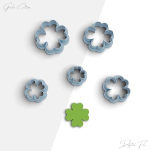 Può includere: Cinque tagliabiscotti in plastica blu a forma di trifoglio a quattro foglie, di diverse dimensioni. È incluso anche un tagliabiscotti a forma di trifoglio a quattro foglie verde.