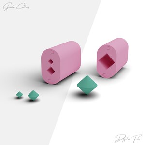 May include: Two pink 3D printed cookie cutters shaped like diamonds, with a smaller diamond-shaped cutter in the foreground. The cutters are on a white background.
