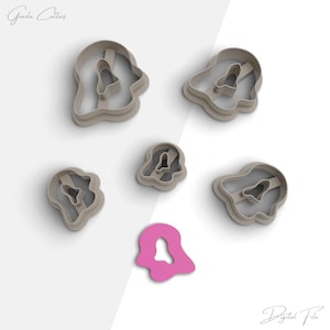 May include: Set of six cookie cutters in the shape of ghosts. The cutters are made of a light brown plastic and are arranged on a white background. The cutters are different sizes and have a small hole in the center of each ghost.