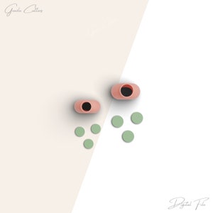 May include: A digital illustration featuring two pink, oval-shaped objects with black interiors, and several small, light green circles. The text "Grazia Cutters" and "Digital File" are visible in the image.