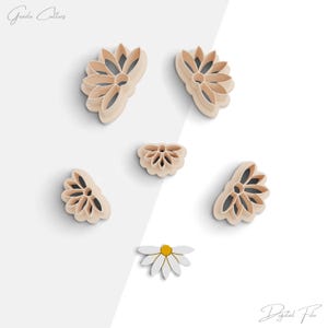 Puede incluir: Un conjunto de seis cortadores de galletas con forma de margaritas. Los cortadores están hechos de plástico marrón claro y están dispuestos sobre un fondo blanco. Los cortadores son de diferentes tamaños y tienen un número variable de pétalos.