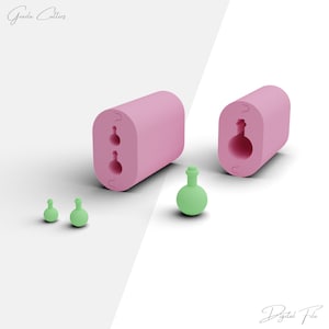 May include: A pink silicone mold with two round cavities shaped like potion bottles. The mold is open and there are three green potion bottles next to it.