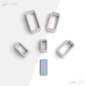 May include: Six different sized rectangle cookie cutters, all in a light purple color, on a white background. The cutters are arranged in a scattered pattern. There is a single, light blue rectangle in the center of the image.