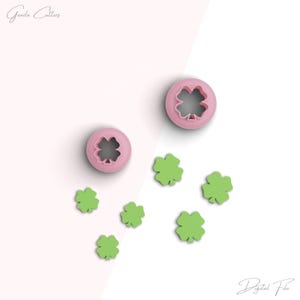 Puede incluir: Dos cortadores de galletas de trébol de cuatro hojas de color rosa y seis formas de trébol de cuatro hojas verdes sobre un fondo blanco y rosa. El texto "Gouda Cutters" está en la esquina superior izquierda y "Digital File" está en la esquina inferior derecha.